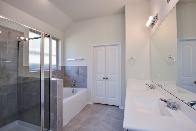 bathroom featuring vanity, independent shower and bath, and vaulted ceiling