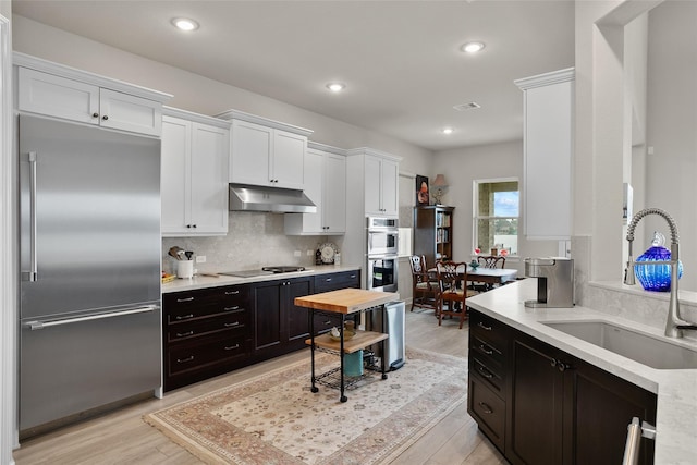 kitchen featuring white cabinetry, sink, decorative backsplash, appliances with stainless steel finishes, and light wood-type flooring