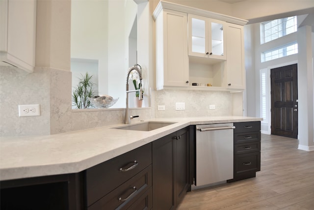 kitchen featuring white cabinets, stainless steel dishwasher, sink, and light hardwood / wood-style flooring