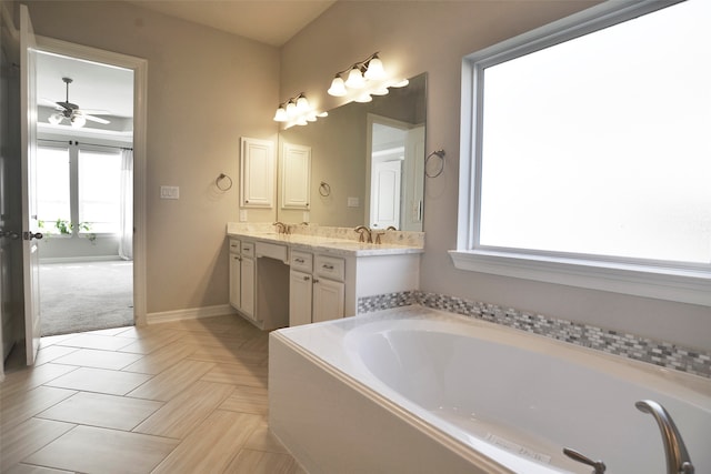 bathroom featuring ceiling fan, a healthy amount of sunlight, a tub, and vanity