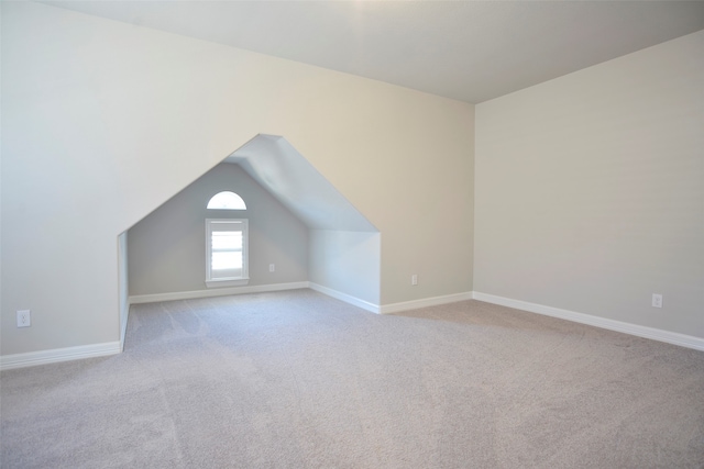 additional living space with light colored carpet and vaulted ceiling