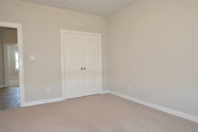 unfurnished bedroom with light colored carpet and a closet