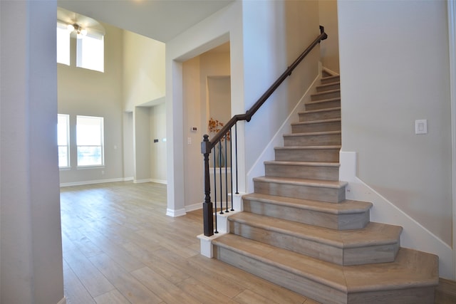 staircase with wood-type flooring and a high ceiling