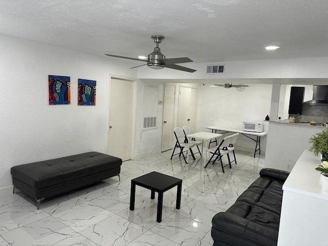 living room featuring ceiling fan and a textured ceiling