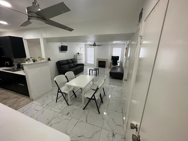 dining space with ceiling fan, sink, and a fireplace