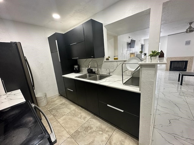 kitchen featuring sink, backsplash, a textured ceiling, black refrigerator, and range