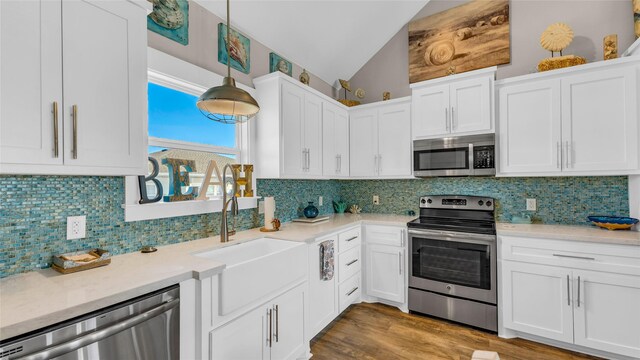 kitchen featuring stainless steel appliances, backsplash, vaulted ceiling, decorative light fixtures, and white cabinets