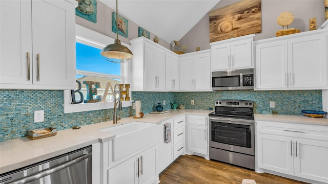 kitchen featuring pendant lighting, white cabinetry, appliances with stainless steel finishes, and lofted ceiling