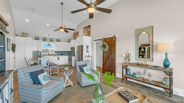 living room with wood-type flooring, a barn door, high vaulted ceiling, and ceiling fan