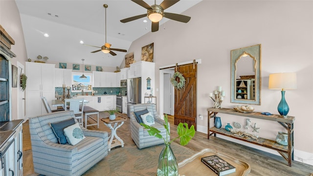 living room featuring ceiling fan, a barn door, hardwood / wood-style floors, and high vaulted ceiling