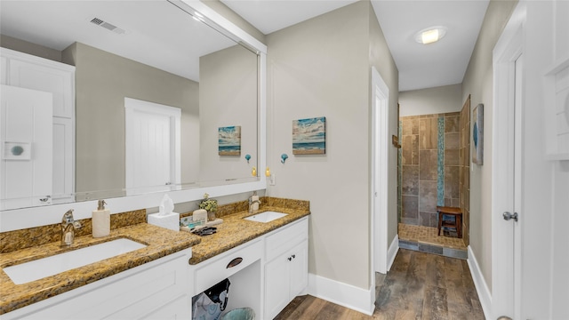 bathroom featuring tiled shower, wood-type flooring, and vanity