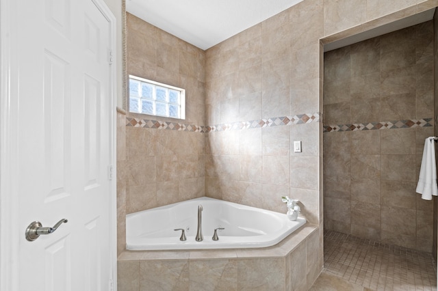 bathroom featuring plus walk in shower and tile walls