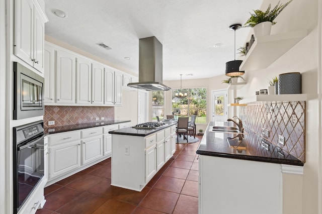 kitchen with island exhaust hood, white cabinets, pendant lighting, and appliances with stainless steel finishes