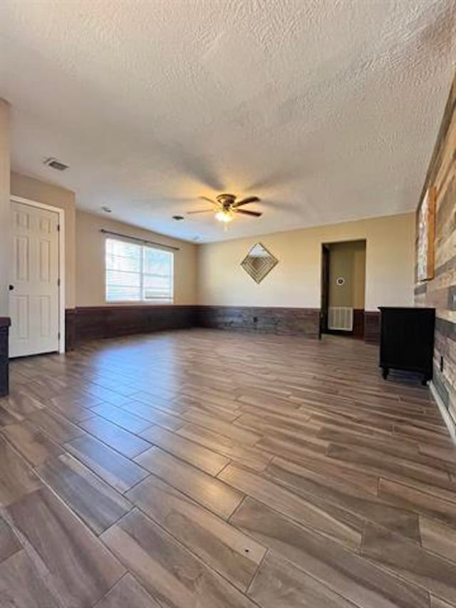 unfurnished living room featuring hardwood / wood-style floors, ceiling fan, and a textured ceiling