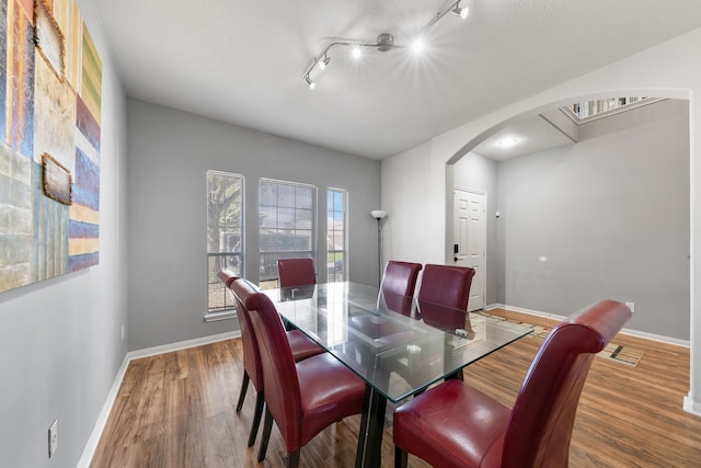 dining room with wood-type flooring and rail lighting