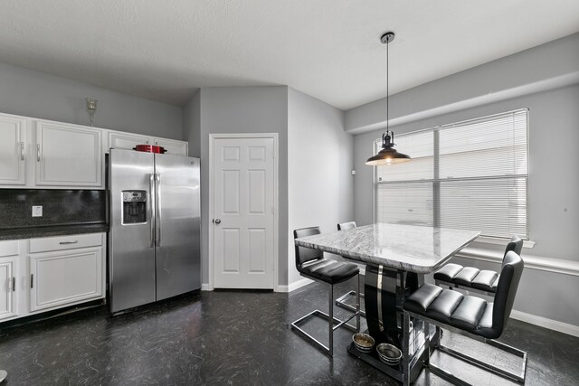 kitchen featuring backsplash, stainless steel fridge, pendant lighting, a kitchen bar, and white cabinets