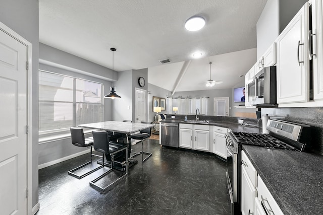 kitchen featuring hanging light fixtures, vaulted ceiling, ceiling fan, appliances with stainless steel finishes, and white cabinetry