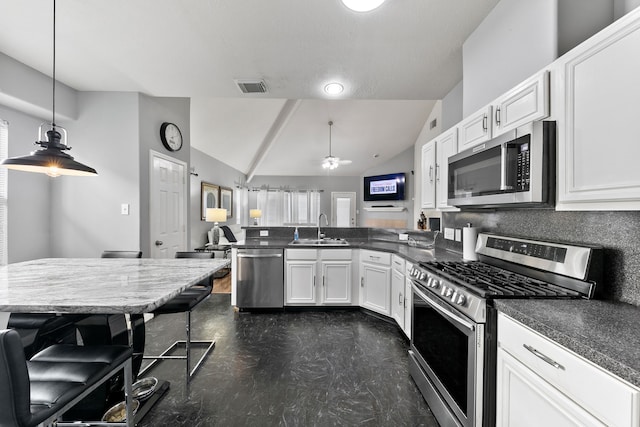 kitchen with lofted ceiling, decorative light fixtures, a kitchen bar, white cabinetry, and stainless steel appliances