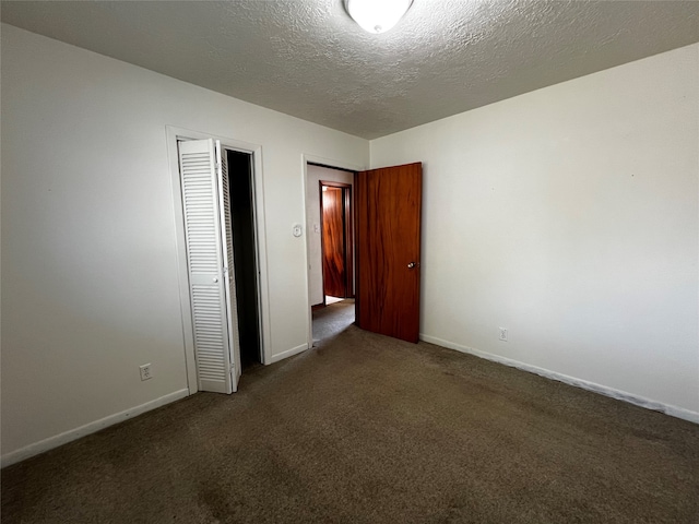 unfurnished bedroom with dark carpet, a textured ceiling, and a closet