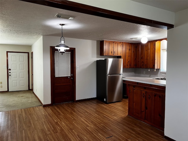 kitchen featuring sink, hanging light fixtures, dark hardwood / wood-style flooring, stainless steel fridge, and a textured ceiling