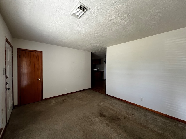 spare room with a textured ceiling and dark carpet