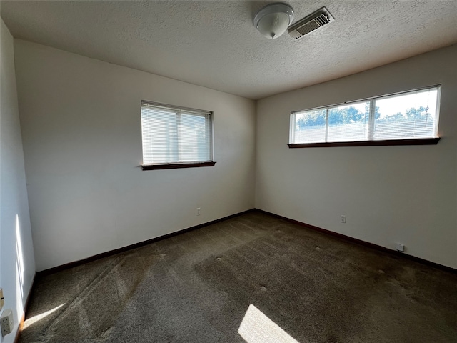 spare room featuring dark colored carpet and a textured ceiling