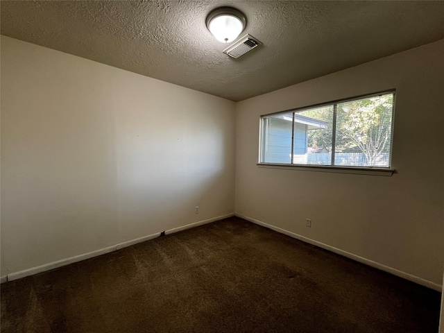 empty room featuring a textured ceiling and dark carpet