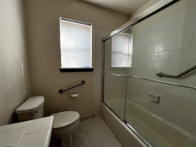 full bathroom with tile patterned floors, toilet, combined bath / shower with glass door, and vanity