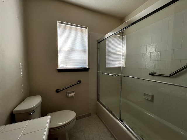 bathroom featuring shower / bath combination with glass door, tile patterned flooring, and toilet