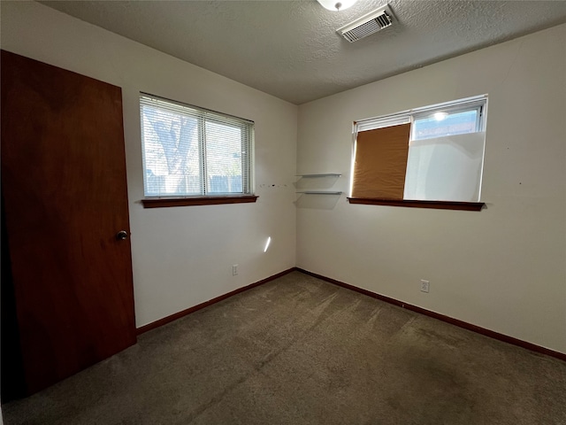 carpeted empty room with a textured ceiling