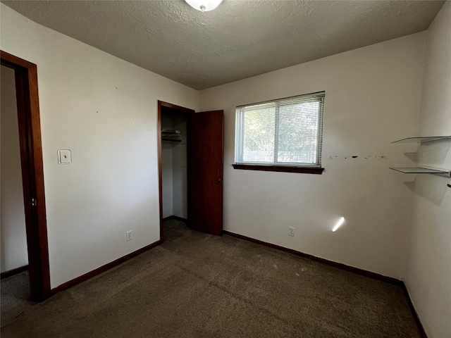 unfurnished bedroom with dark colored carpet, a textured ceiling, and a closet