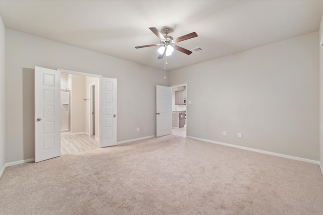 unfurnished bedroom featuring ceiling fan, light colored carpet, and ensuite bathroom