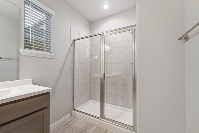 bathroom with wood-type flooring, vanity, and a shower with door