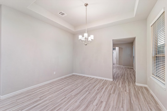 unfurnished room with light hardwood / wood-style floors, a raised ceiling, and an inviting chandelier