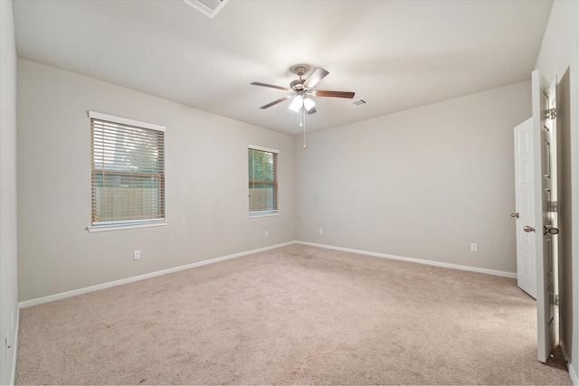 unfurnished room featuring ceiling fan, light colored carpet, and a wealth of natural light