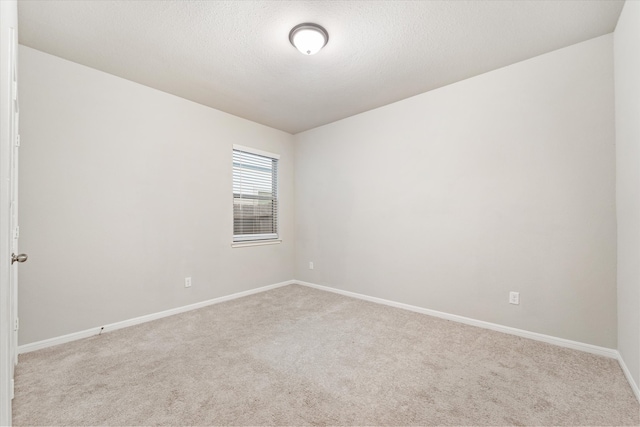 unfurnished room with light colored carpet and a textured ceiling