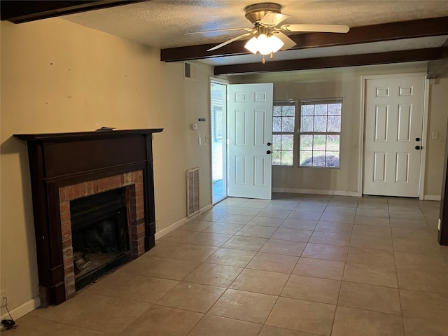 unfurnished living room featuring a brick fireplace, a textured ceiling, ceiling fan, light tile patterned floors, and beamed ceiling