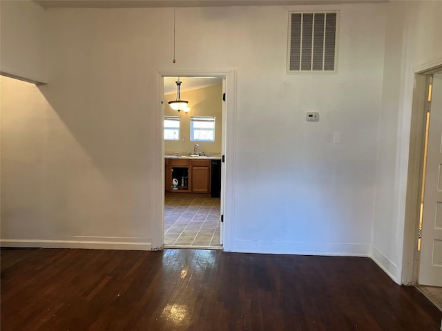 spare room featuring dark hardwood / wood-style floors, lofted ceiling, and sink