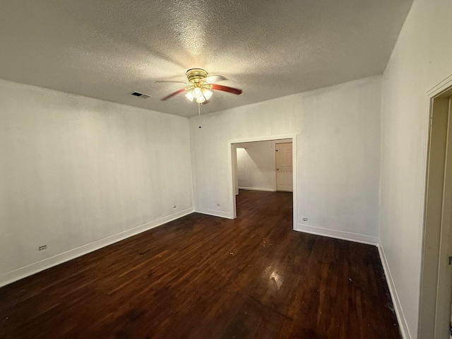 empty room with a textured ceiling, ceiling fan, and dark hardwood / wood-style floors