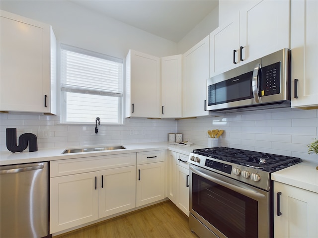 kitchen featuring decorative backsplash, appliances with stainless steel finishes, white cabinets, and sink