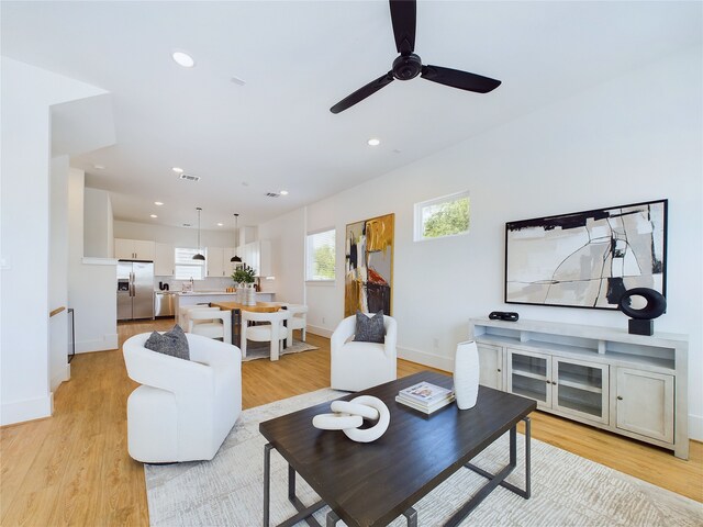 living room featuring light hardwood / wood-style flooring, ceiling fan, and sink