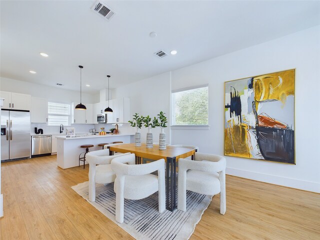 dining room with sink, plenty of natural light, and light wood-type flooring