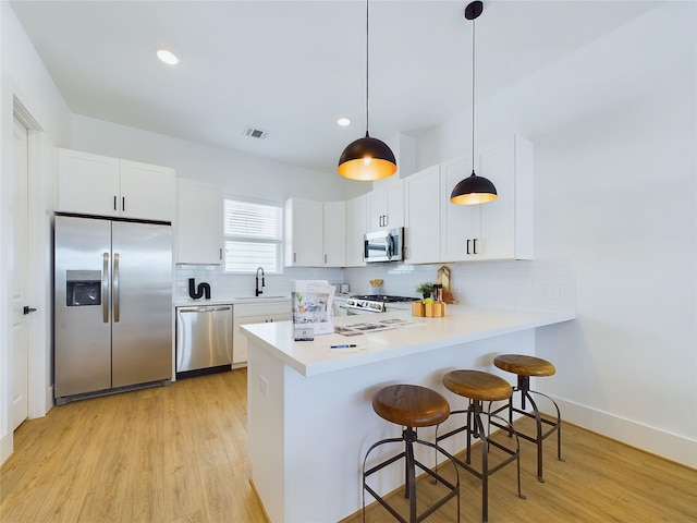 kitchen with decorative light fixtures, stainless steel appliances, white cabinetry, and sink