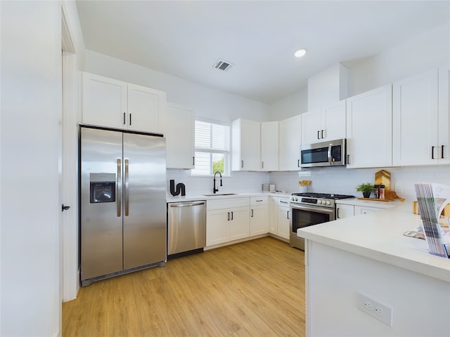 kitchen with white cabinets, appliances with stainless steel finishes, light wood-type flooring, and sink