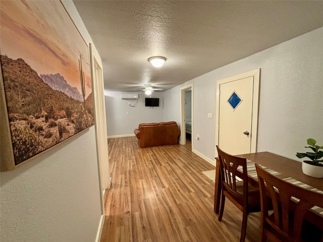 hall featuring an AC wall unit, light hardwood / wood-style floors, and a textured ceiling