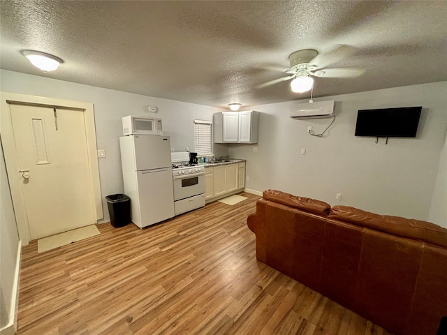 living room featuring a wall unit AC, ceiling fan, light hardwood / wood-style floors, and a textured ceiling