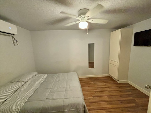 unfurnished bedroom with a textured ceiling, hardwood / wood-style flooring, an AC wall unit, and ceiling fan