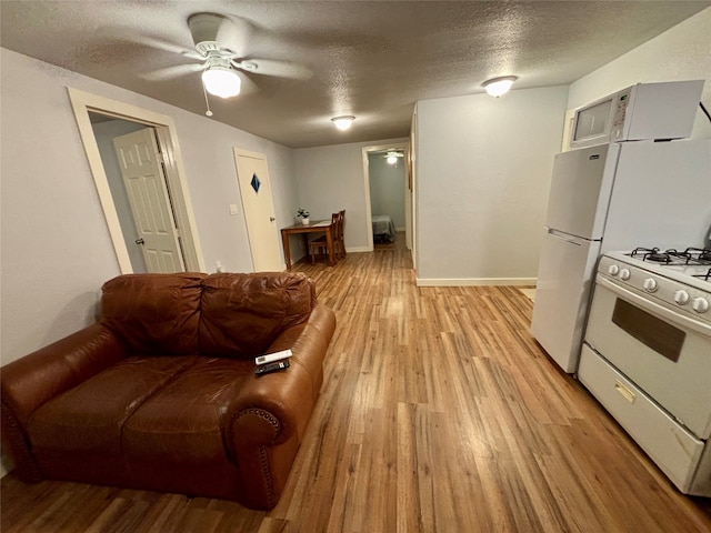 living room with ceiling fan, light wood-type flooring, and a textured ceiling