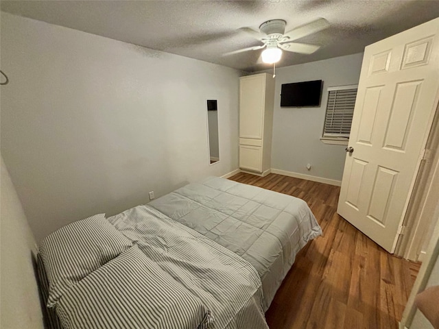 bedroom featuring a textured ceiling, ceiling fan, and dark wood-type flooring