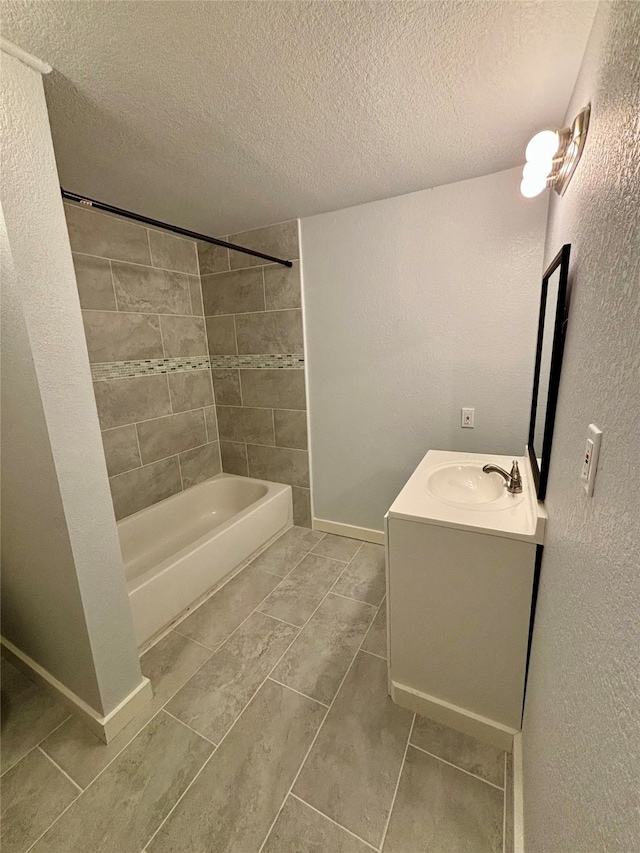 bathroom with a textured ceiling, vanity, tiled shower / bath combo, and tile patterned floors